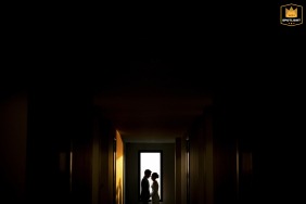 Soft light spills into a doorway at Neera Retreat Hotel in Thailand, where a couple is silhouetted indoors, their outlines creating a striking and intimate portrait.